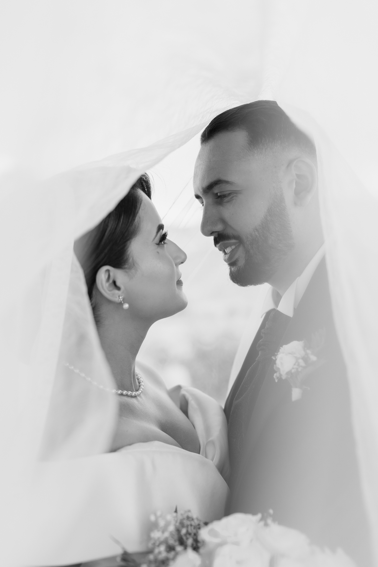Photographe de mariage à Marseille, instant intime sous le voile avec un baiser tendre entre les mariés, lumière douce et émotion.