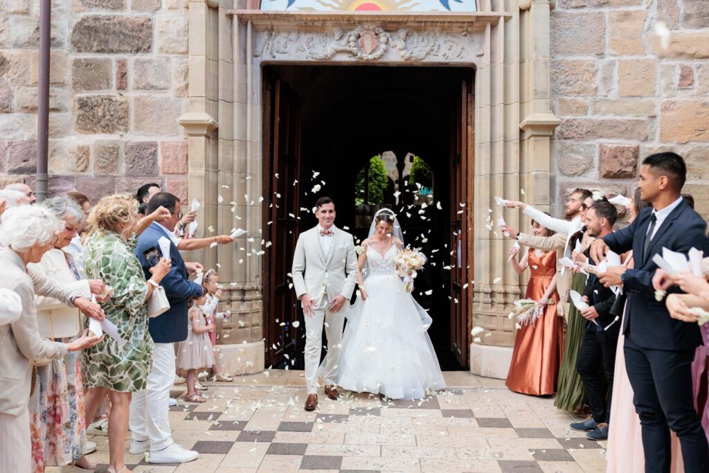 Sortie de la cathédrale de Fréjus de Léa et Charles sous une pluie de pétales, entourés de leurs proches après la cérémonie religieuse