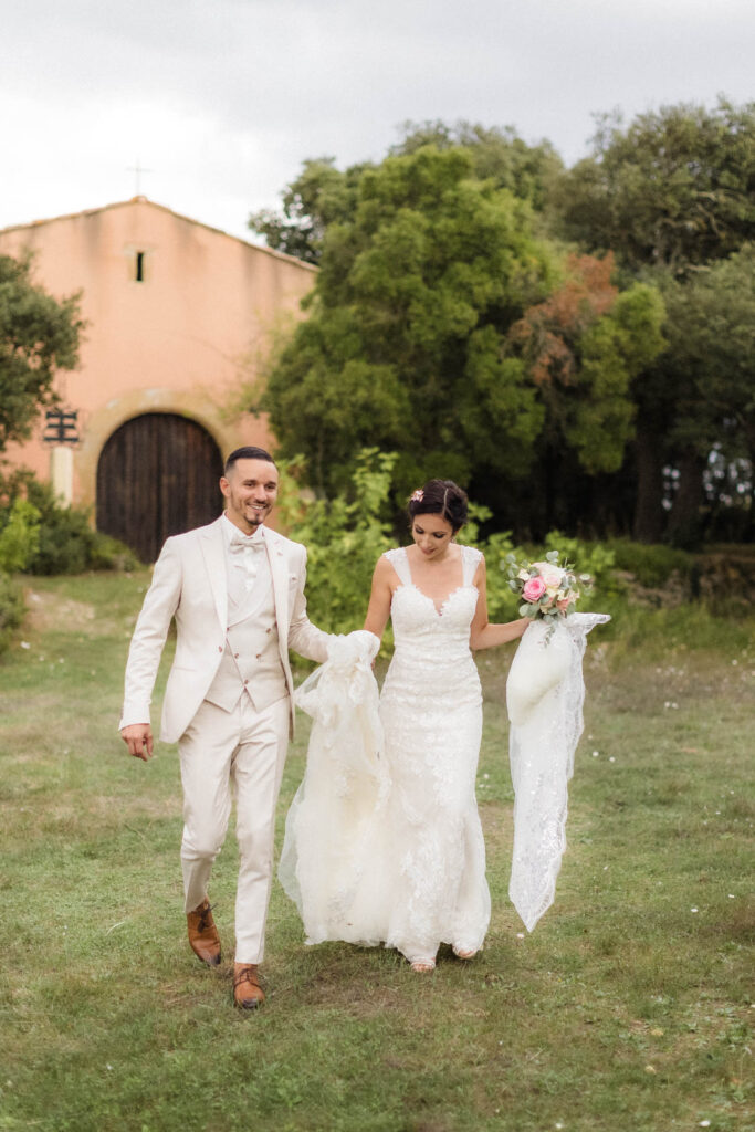 Le couple marche main dans la main, avec la chapelle du Salon du Mirapier en arrière-plan